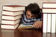 Erschöpfter schläft zwischen gestapelten Büchern