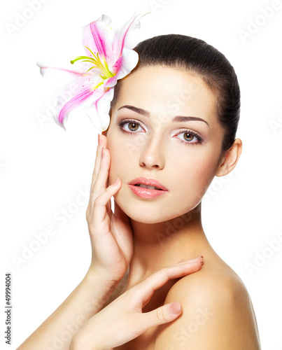 Photo: Beauty face of young woman with flower. Beauty treatment concept Beauty face of young woman with flower. Beauty treatment concept