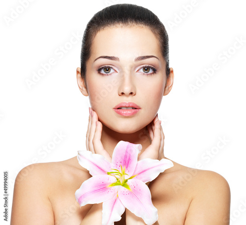 Photo: Beauty face of young woman with flower. Beauty treatment concept Beauty face of young woman with flower. Beauty treatment concept