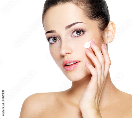 Photo: Beauty face of young woman with cosmetic cream on a cheek. Beauty face of young woman with cosmetic cream on a cheek.