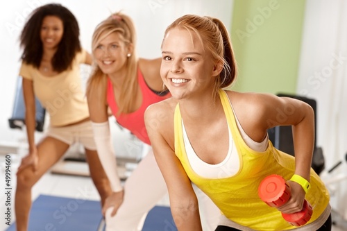 Photo: Fit girl exercising with dumbbells smiling Fit girl exercising with dumbbells smiling