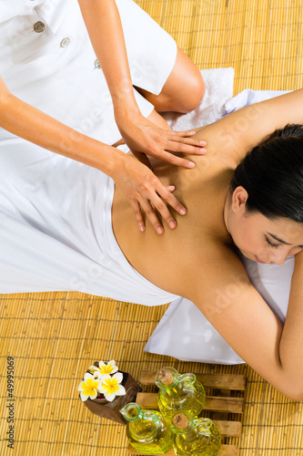 Photo: Asian woman having a massage in tropical setting Asian woman having a massage in tropical setting