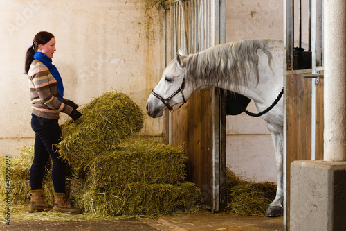 Photo: Woman and haystacks, white horse watching alongside Woman and haystacks, white horse watching alongside