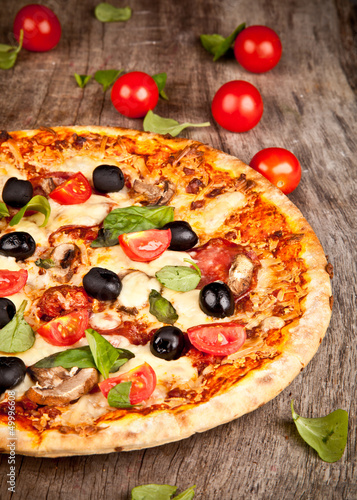 Photo: Delicious italian pizza served on wooden table Delicious italian pizza served on wooden table