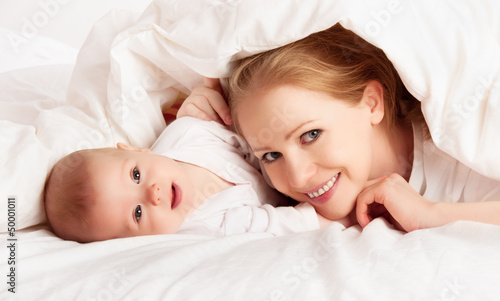 Photo: happy family. Mother and baby playing under blanket happy family. Mother and baby playing under blanket
