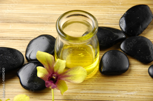Photo: Massage oil and black stones with orchid Massage oil and black stones with orchid