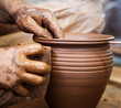 Potter hands making in clay on pottery wheel.