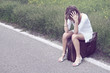 Photo: Desperate young girl on a suitcase at the border of a road Desperate young girl on a suitcase at the border of a road