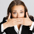 Business woman covering mouth, over gray