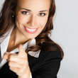 Businesswoman pointing finger at viewer, over gray