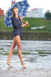 Beautiful blonde woman holding umbrella out in the spring rain
