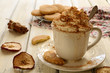 Cup of whipped cream coffee and apple cookies on wooden table