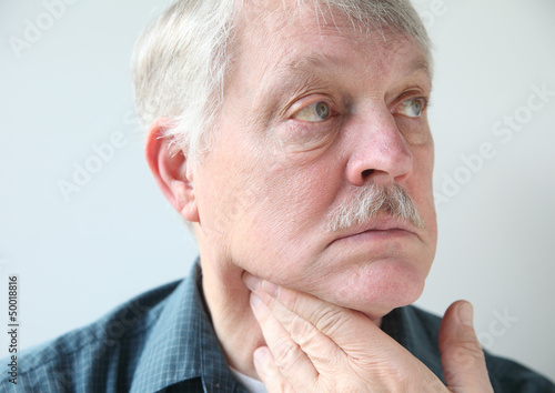 Photo: older man with a sore throat or neck older man with a sore throat or neck