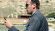 Businessman with cellphone standing on the beach, slow motion sh