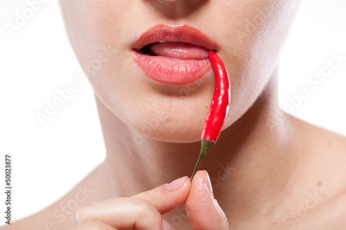 Photo: Young woman with chili pepper isolated on white Young woman with chili pepper isolated on white