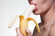 Photo: Young woman biting banana isolated on white Young woman biting banana isolated on white