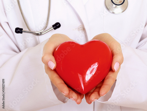 Photo: Female doctor standing with stethoscope and red heart symbol Female doctor standing with stethoscope and red heart symbol