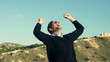 Man raised hands on top of a mountain enjoying view, slow motion