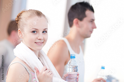 Photo: Man and woman drinking water after sports in gym Man and woman drinking water after sports in gym