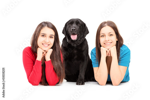 Photo: Two young females lying and posing with a dog Two young females lying and posing with a dog