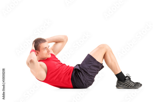 Photo: Young man doing abbs on the floor Young man doing abbs on the floor