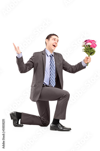Photo: Young man kneeling and holding a bunch of flowers Young man kneeling and holding a bunch of flowers
