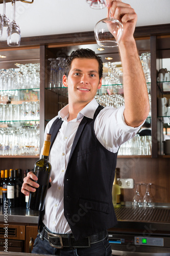 Photo: Barman standing behind bar with wine Barman standing behind bar with wine
