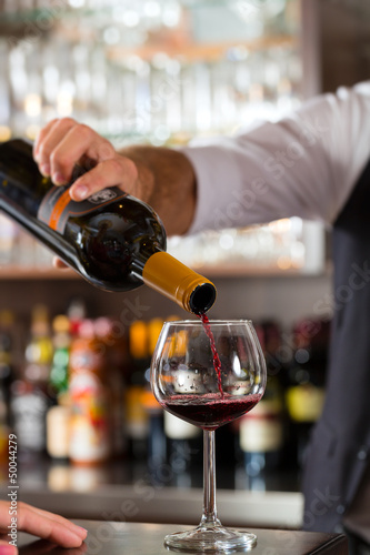 Photo: Red wine pouring in glass at bar Red wine pouring in glass at bar