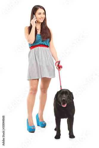 Photo: Full length portrait of a female walking her dog and talking on Full length portrait of a female walking her dog and talking on