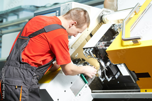 Photo: worker operating CNC machine center worker operating CNC machine center
