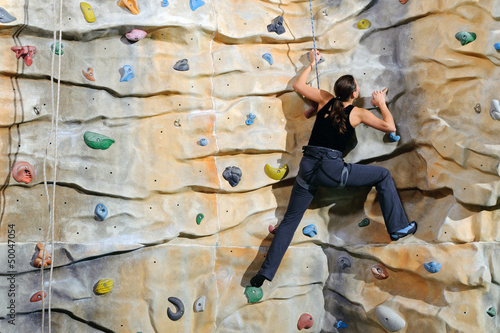 Photo: woman on rock wall in sport centre woman on rock wall in sport centre