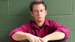 Depressed man sitting against a wall