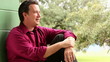 Happy man sitting against a wall