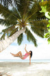Happy woman relaxing in hammock on a tropical beach
