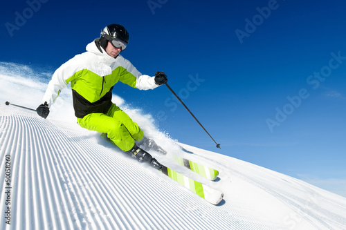 Photo: Skier in mountains, prepared piste and sunny day Skier in mountains, prepared piste and sunny day