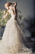 Bride in wedding dress behind bush with flowers