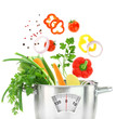 Fresh vegetables falling into a casserole pot with weight scale