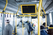 Modern city bus with passengers and information screens under ce