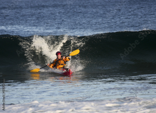 Photo: Kayak surfer escaping from big wave on rough sea Kayak surfer escaping from big wave on rough sea