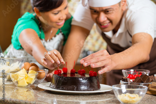 Photo: Asian couple baking chocolate cake in kitchen Asian couple baking chocolate cake in kitchen