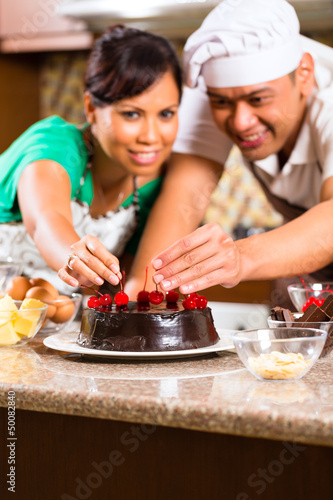 Photo: Asian couple baking chocolate cake in kitchen Asian couple baking chocolate cake in kitchen
