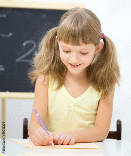 Photo: Little girl is writing using a pen Little girl is writing using a pen