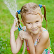 Happy girl pours water from a hose