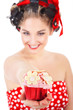 Junge sexy Frau in  Pin Up Style überreicht lachend Cupcake