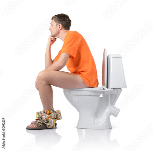 Photo: Thoughtful man sitting on the toilet, white background Thoughtful man sitting on the toilet, white background