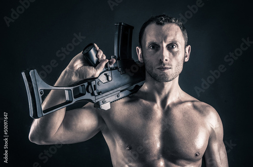 Photo: Confident young man shirtless portrait with machine gun Confident young man shirtless portrait with machine gun