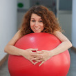Photo: Funny portrait of young woman with ball in the gym. Funny portrait of young woman with ball in the gym.