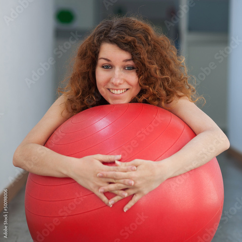 Photo: Funny portrait of young woman with ball in the gym. Funny portrait of young woman with ball in the gym.