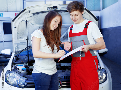 Photo: Car mechanic and female customer look at the repair costs Car mechanic and female customer look at the repair costs