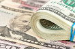 Folded dollar bills wrapped by rubber on money background